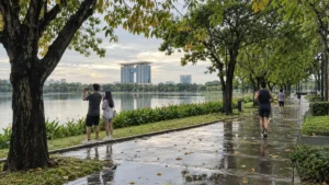 雨上がりのビンズオン新都市公園で湖畔の並木道を歩く人々
