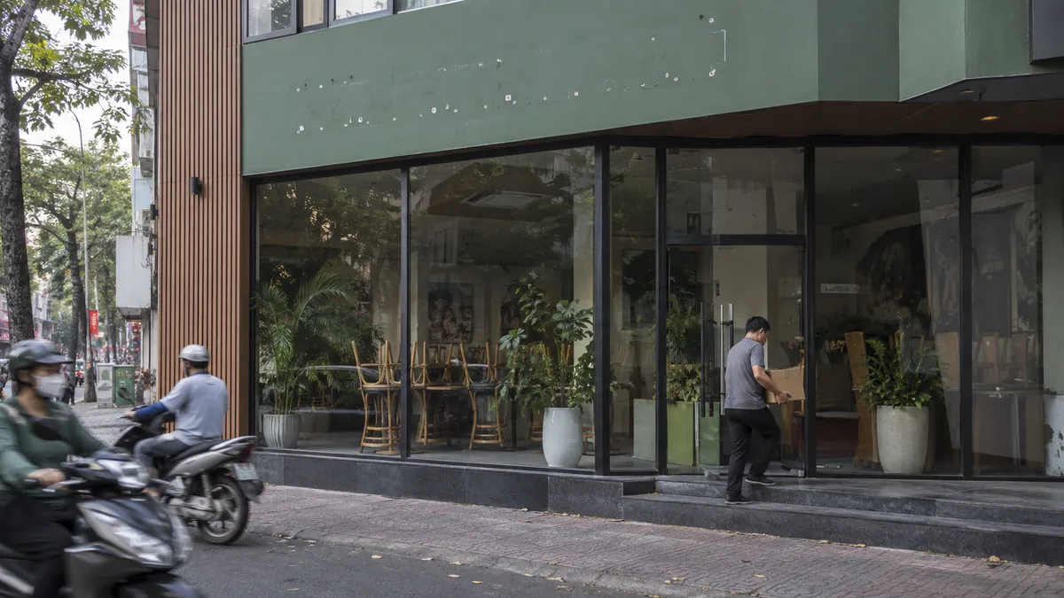 ベトナムで営業を終えたカフェ店舗から備品を運び出す作業員