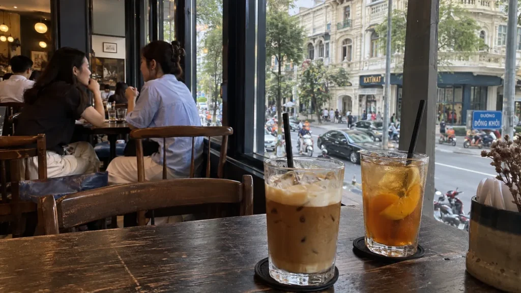 ホーチミン中心部の窓際席に置かれたソルトコーヒーとピーチティー
