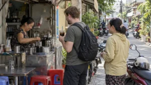 ホーチミン市の路地のコーヒー店で砂糖なしのアイスブラックコーヒーを受け取る旅行者