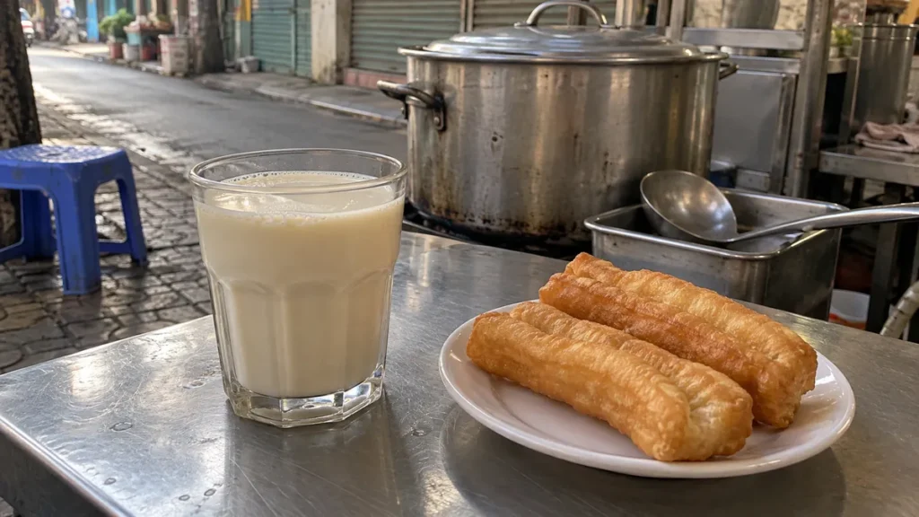 サイゴンの朝の路上販売で飲む豆乳と揚げパンを題材にしたイメージ。パリでの食の記憶と現地の日常の違いを表し、Tom Pham本人の体験や実在の店を再現した写真ではありません。