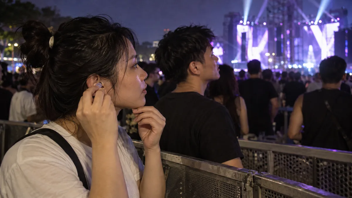 野外EDMイベントで耳栓を着けて音楽を聴く成人のイメージ(Ravolution・ASOTの実際の会場・出演者・観客の写真ではありません)