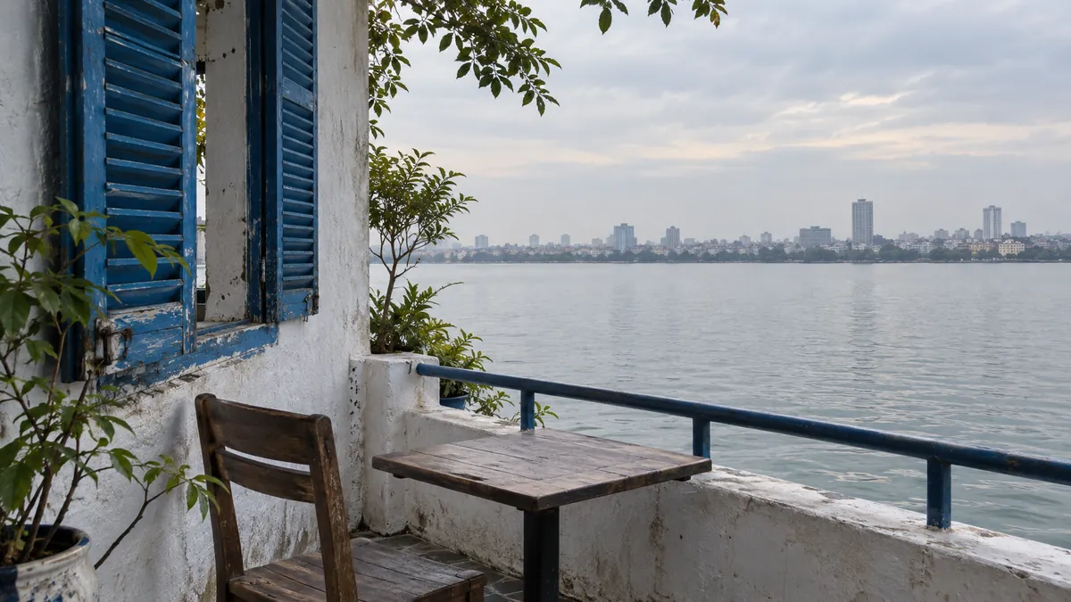 白壁と青い窓枠を配した湖畔カフェの眺めのイメージ。Santorini Vibes Cafeの実際の外観や現在の営業状況を示す写真ではありません