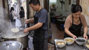 ハノイ旧市街の路地店で三種の温かい甘味を仕上げる家族